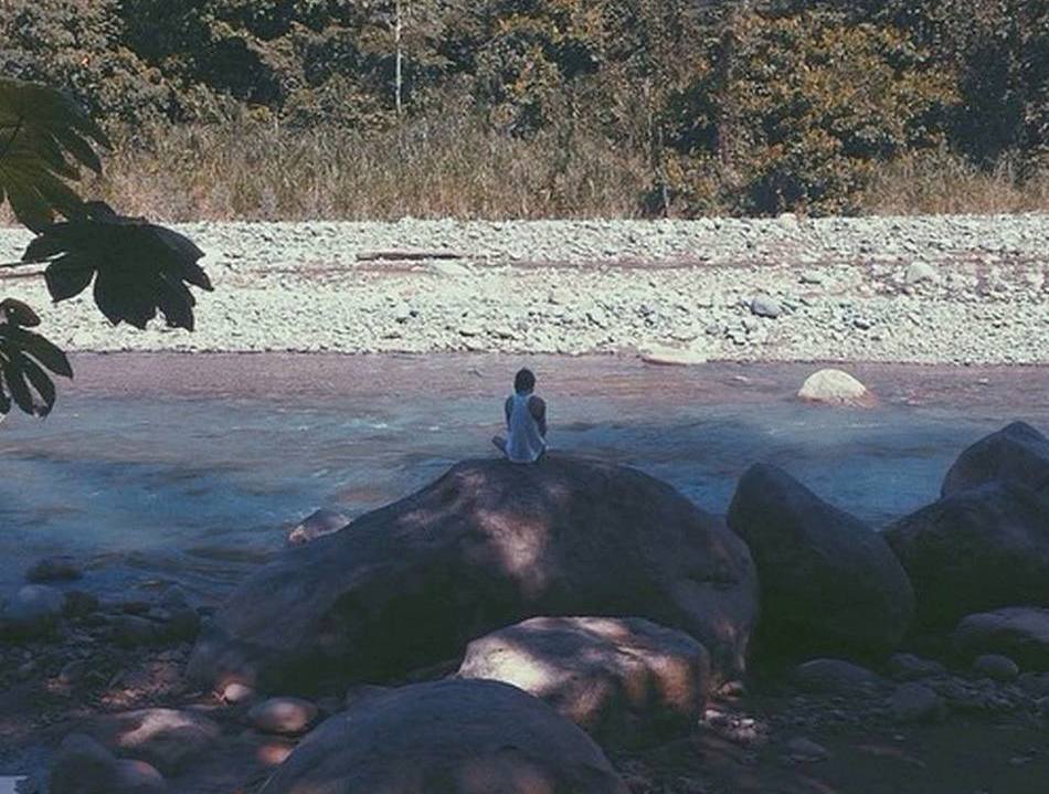 photo of rita solo sitting on rock by the river in costa rica