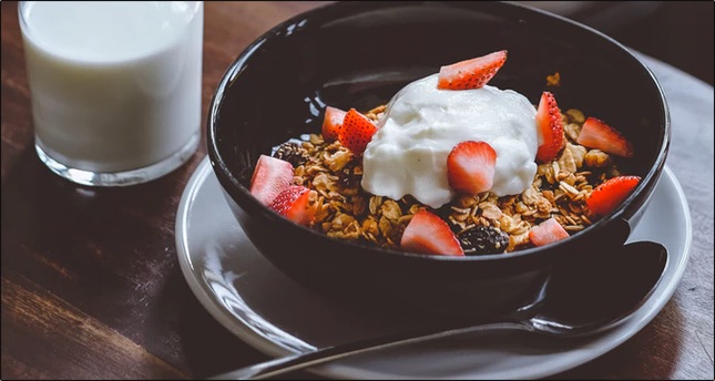 bowl with granola, berries beside a glass of milk