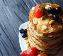 plate of pancakes with syrup and berries